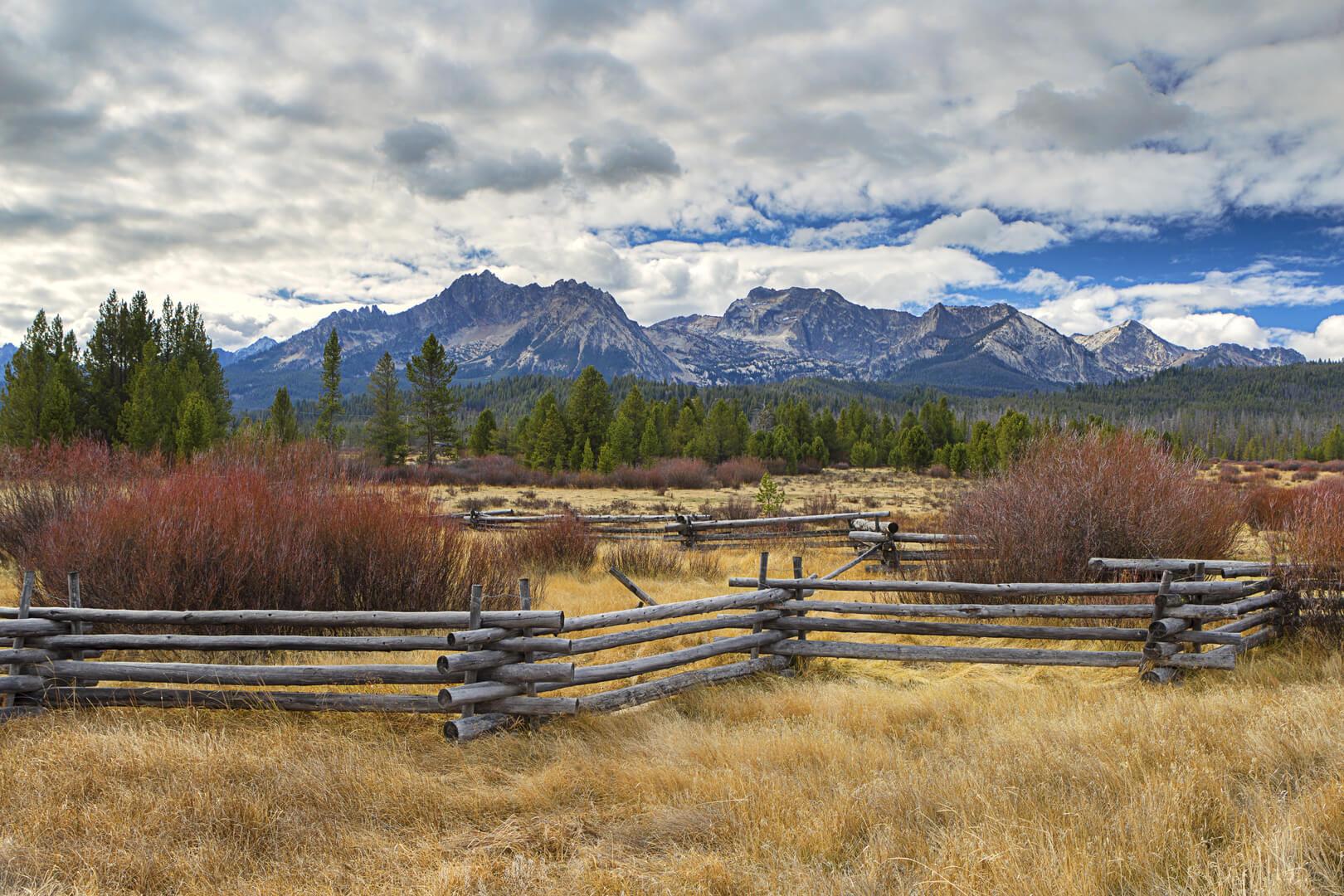 Split-rail fence with pasture, evergreen trees, and Idaho's Sawtooth mountains in the background