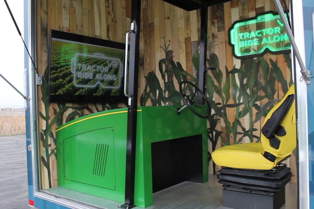 Angled view of virtual reality tractor experience, showing the attract screen and tractor seat