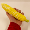Hand holding one artificial corncob