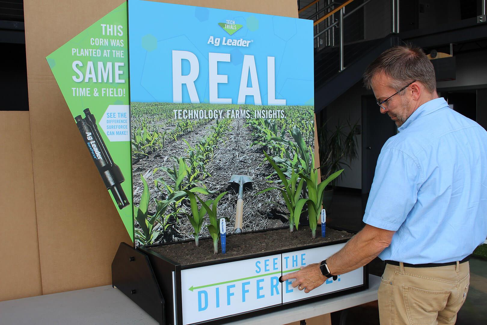 A man standing in front of Ag Leader's planting technology display about to slide the panels open