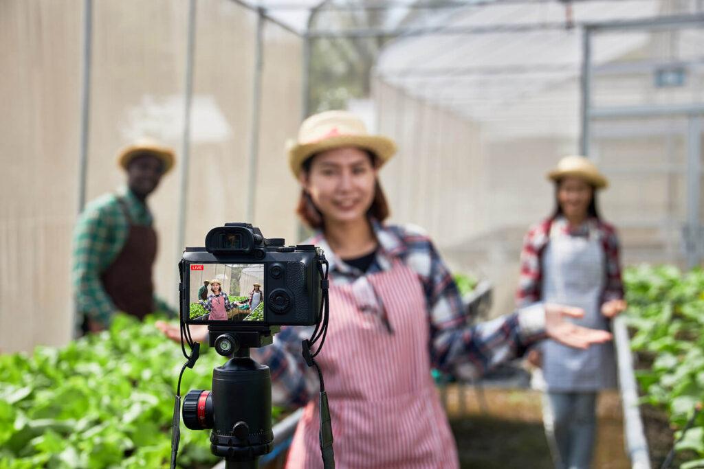 Three farmers in a greenhouse standing in front of a camera.
