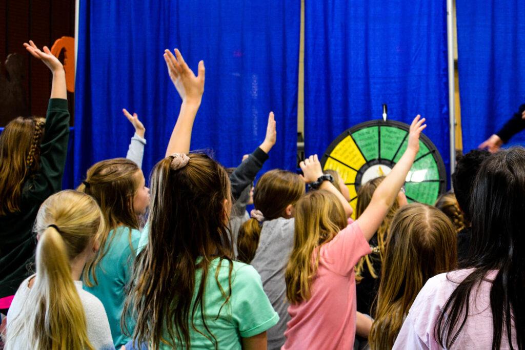 Children raising their hands at a presentation hosted by North Dakota Corn.
