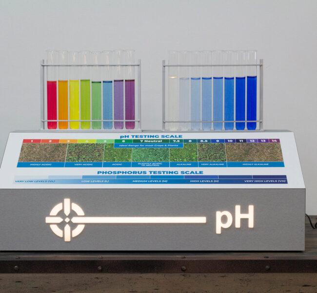 Silver unit holding multi-colored test tubes displays info about testing soil pH levels.