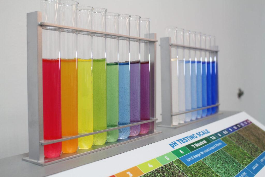 Two racks of colored test tubes on pH display. One is a rainbow gradient, the other is a gradient from clear to dark blue.